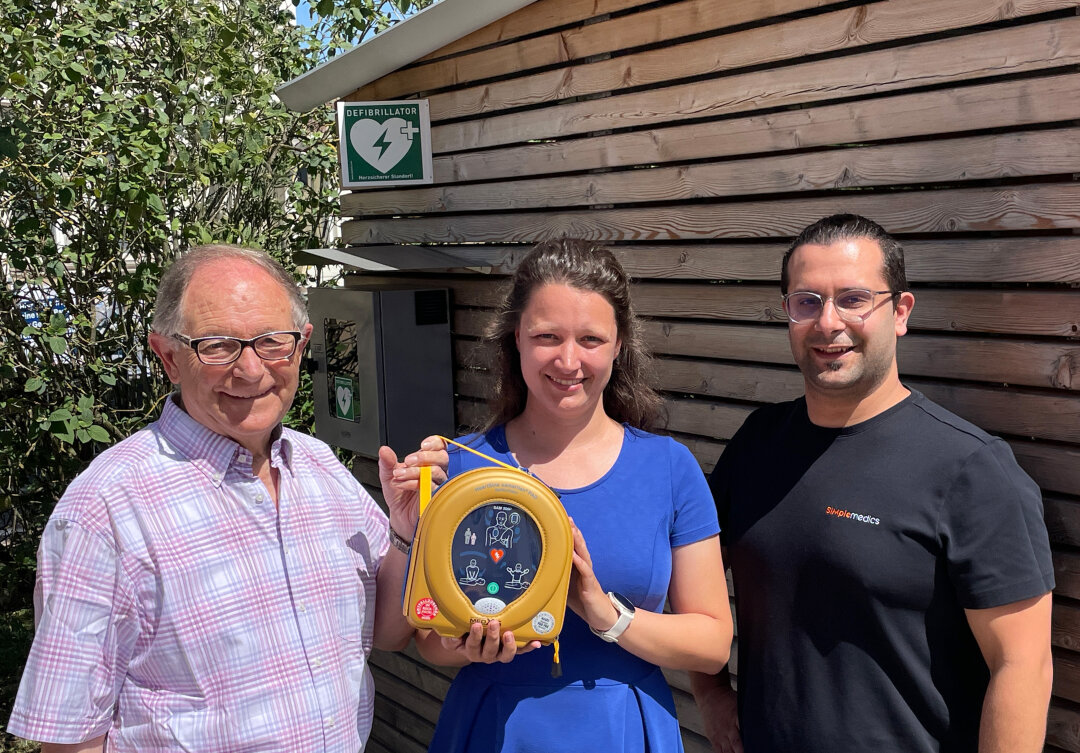 Dritter Bürgermeister Anton Gollmitzer, Ständige Vertreterin der ADBV-Leitung Anna Guggemos und Fabian Lindinger, Geschäftsführer von SIMple medics, zeigen den Standort des Defibrillators am Amt für Digitalisierung, Breitband und Vermessung Günzburg. 